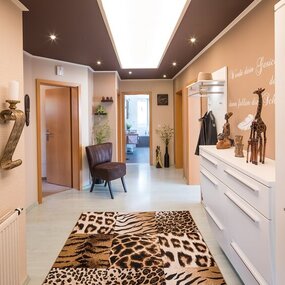 Moderner Flur mit afrikanischen Dekorationen, Tiermuster-Teppich und stilvoller Beleuchtung.