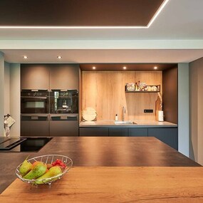 Moderne offene Küche mit Kochinsel, Obstschale und stilvoller Beleuchtung.