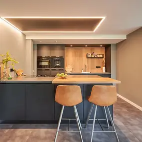 Moderne offene Küche mit Kochinsel, Barhockern und stilvoller LED-Deckenbeleuchtung.