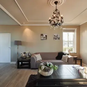 Modernes Wohnzimmer mit Kronleuchter, beiger Couch, Dekoration und großem Fenster.