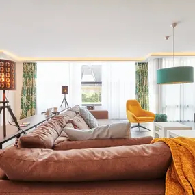 Modernes Wohnzimmer mit großen Fenstern, gemütlichem Sofa und stilvoller Beleuchtung.
